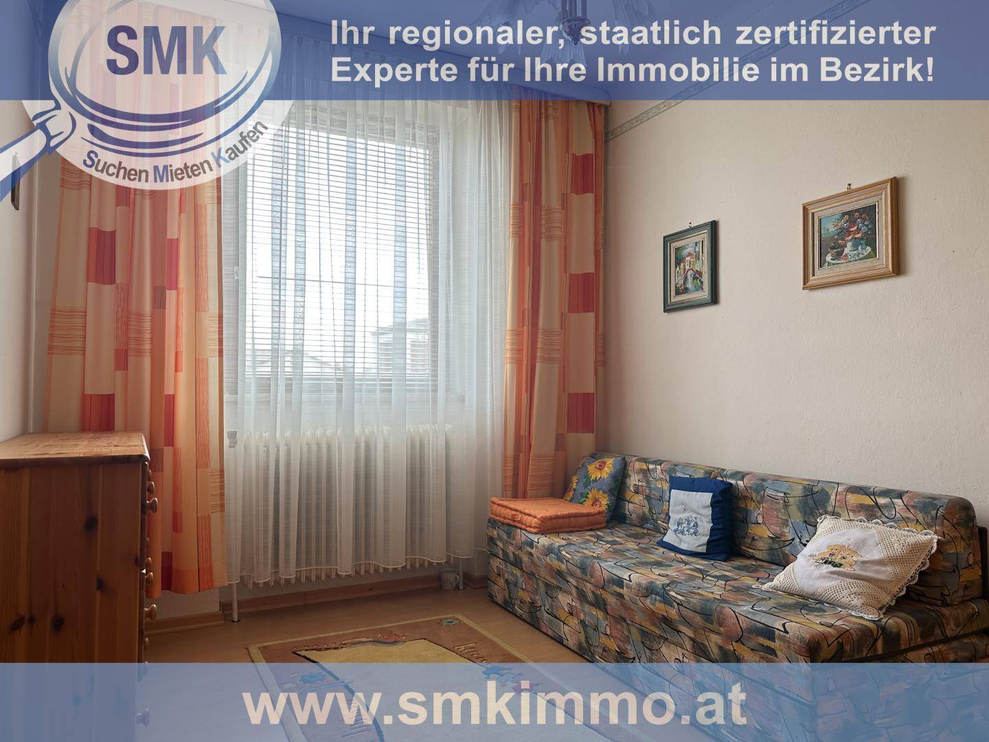 Kleines Wohnzimmer mit Sofa, Fenster und Vorhängen.