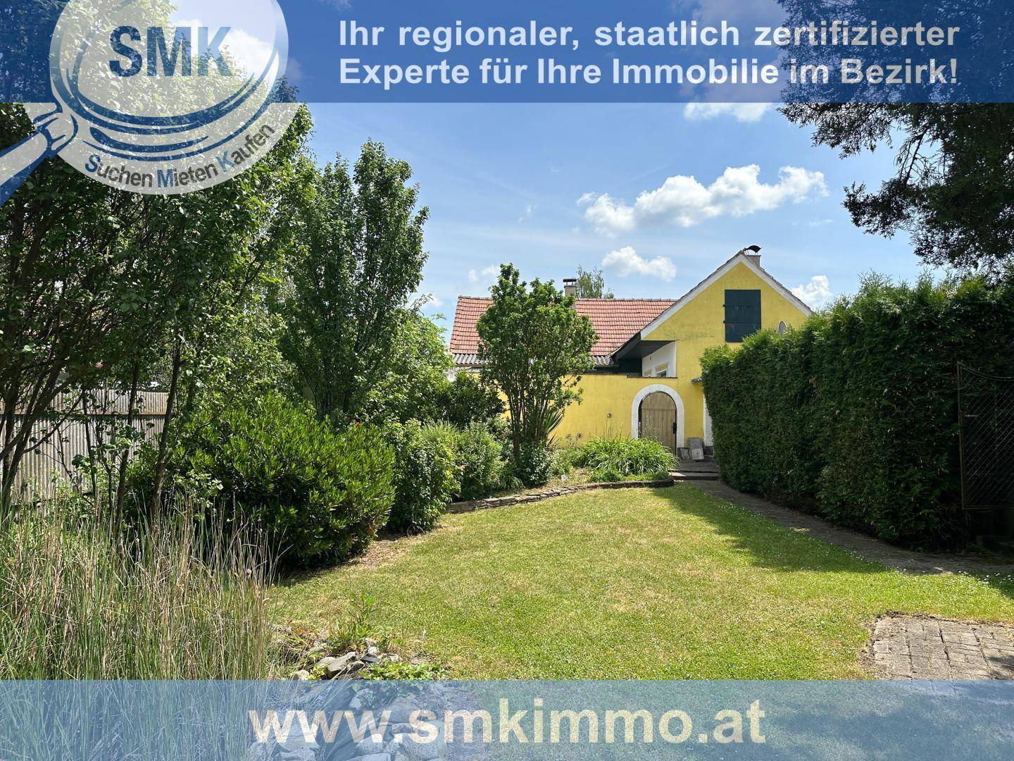 Grüner Garten mit Rasenfläche und Blick auf das gelbe Haus im Hintergrund.