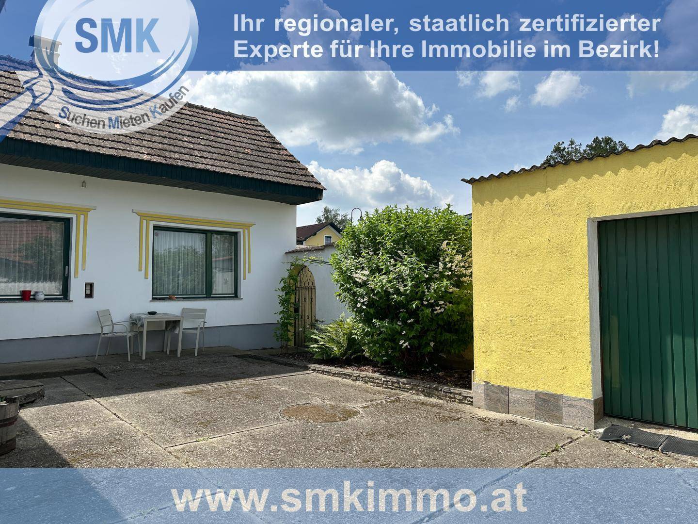 Gepflasterter Hofbereich mit Garage und Sitzgelegenheit im Freien.