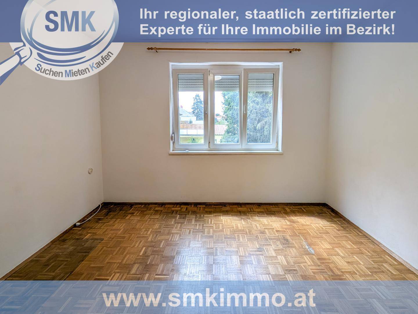 Heller Raum mit Parkettboden, weißen Wänden und großem Fenster mit Rollladen.
