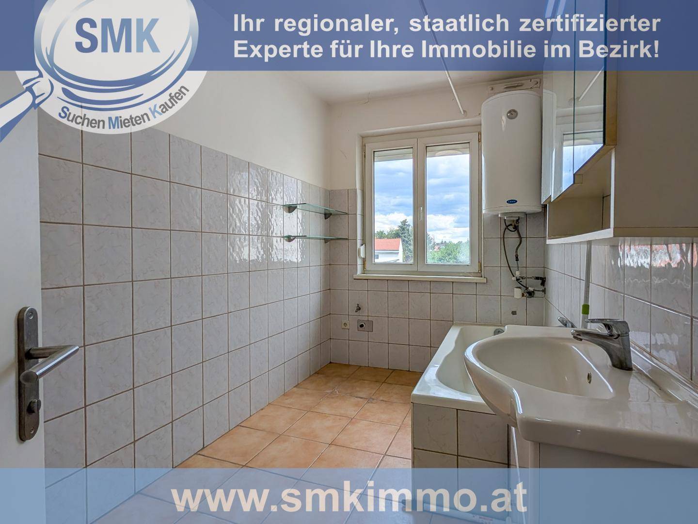 Badezimmer mit weißen Fliesen, Badewanne, Waschbecken und Fenster für Tageslicht.