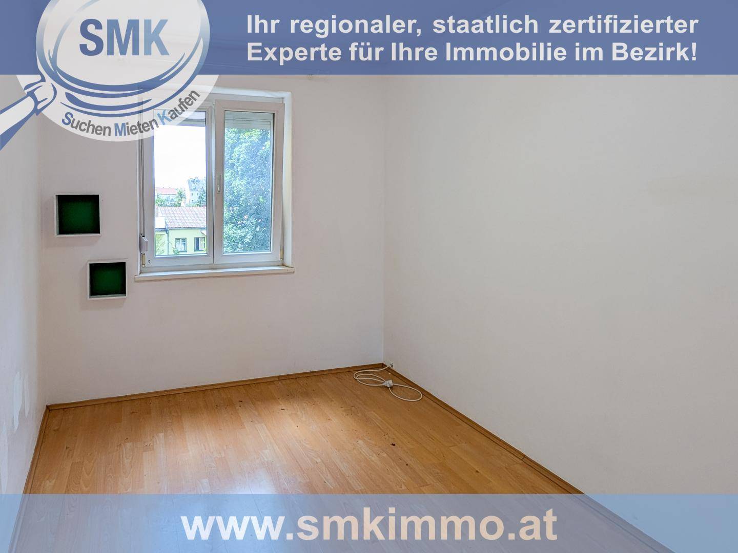 Leerer Raum mit Holzfußboden, weißen Wänden und einem Fenster mit Rollladen.