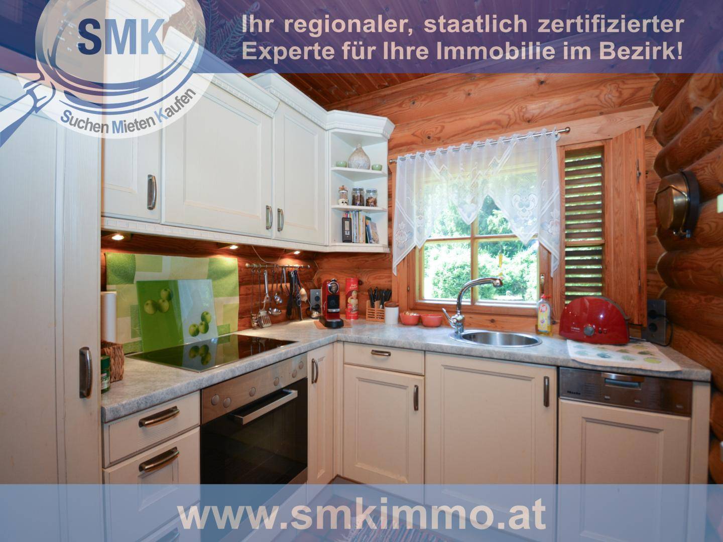 Helle Küche mit weißen Schränken, Holzwänden und Fenster mit Blick ins Grüne.