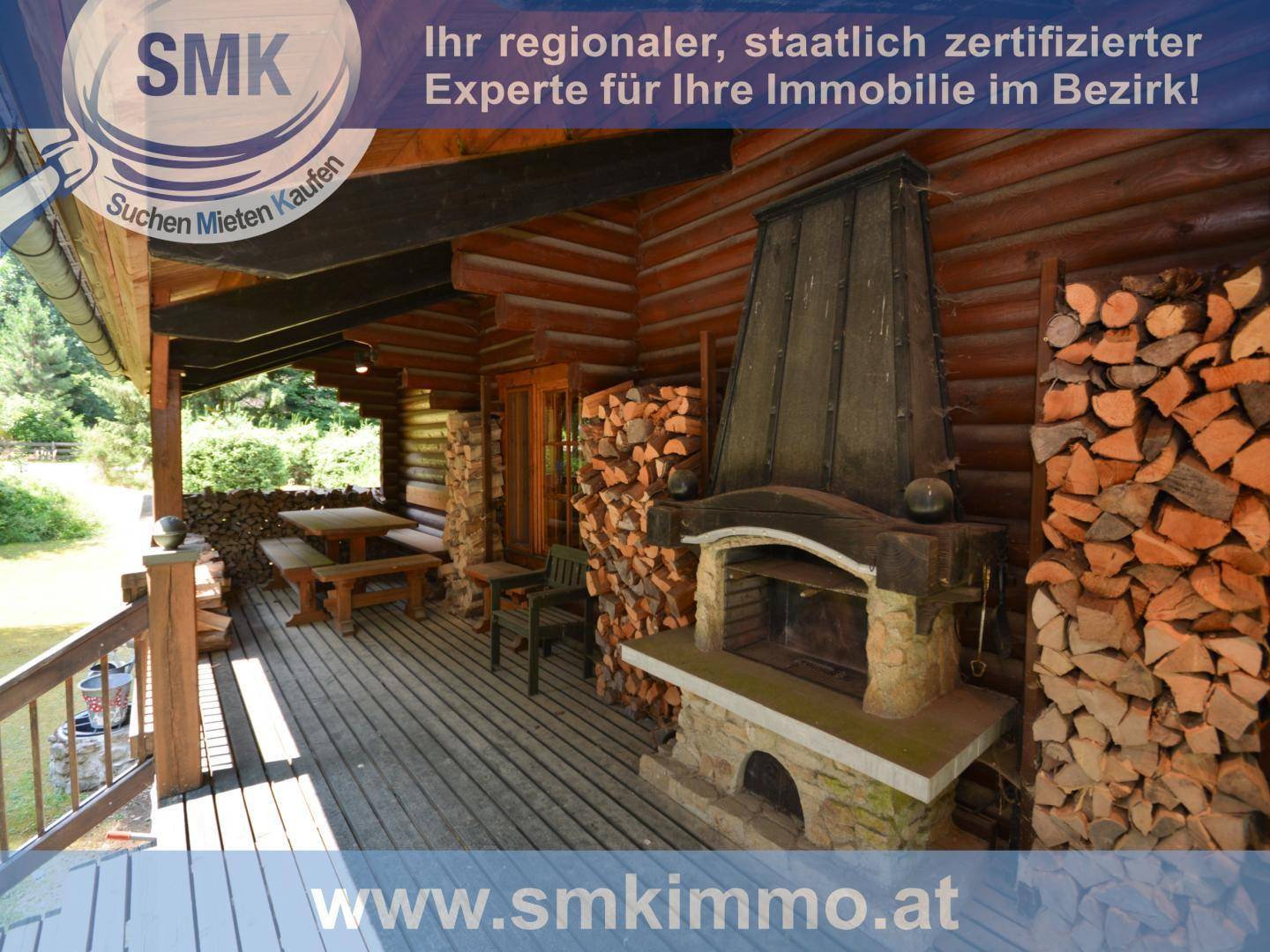Überdachte Holzterrasse mit großem Steinkamin und reichlich Brennholz gestapelt.