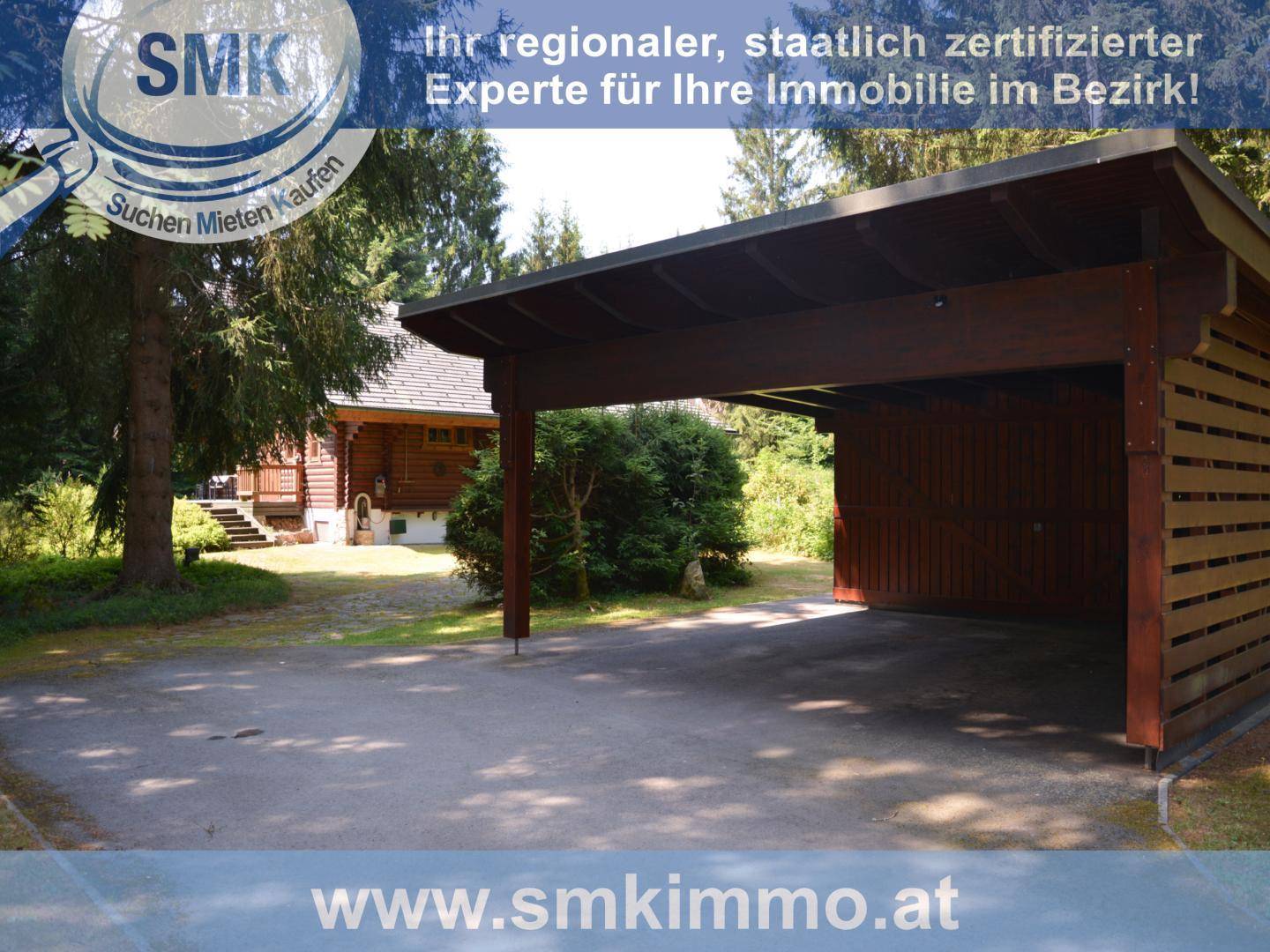 Geräumiger Holzcarport neben der Blockhütte, umgeben von viel Grün und Bäumen.