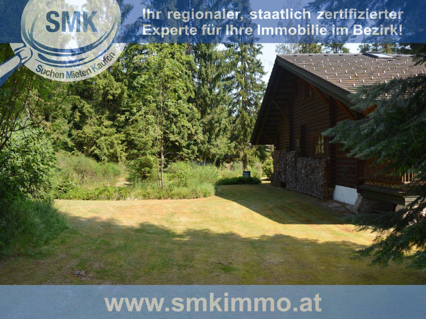 Gepflegte Rasenfläche neben der Blockhütte, umgeben von Bäumen und Sträuchern.