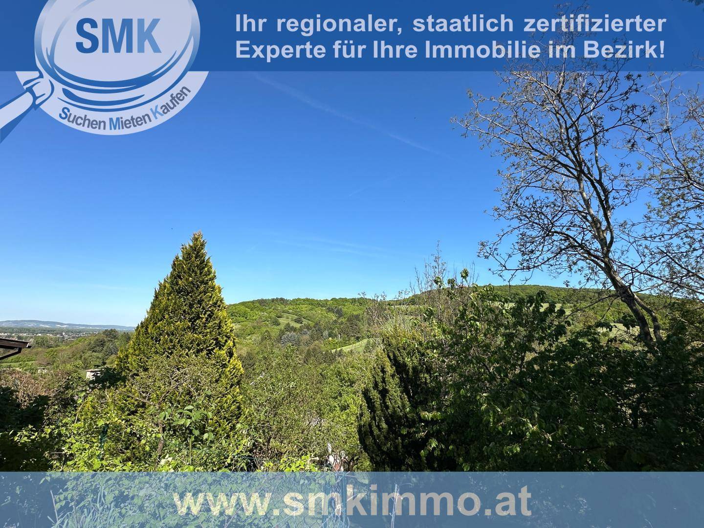 Weitläufiger Panoramablick über eine grüne, hügelige Landschaft mit Bäumen und klarem Himmel.