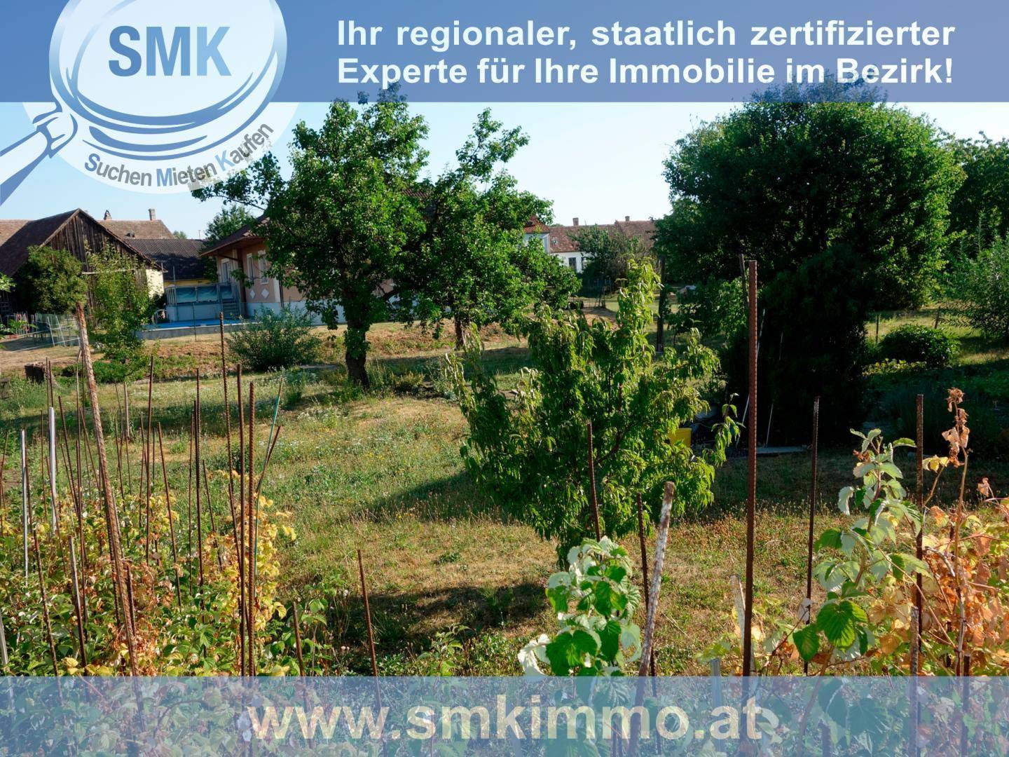 Weitläufiges Gartengrundstück mit Bäumen, Sträuchern und ländlicher Bebauung im Hintergrund.