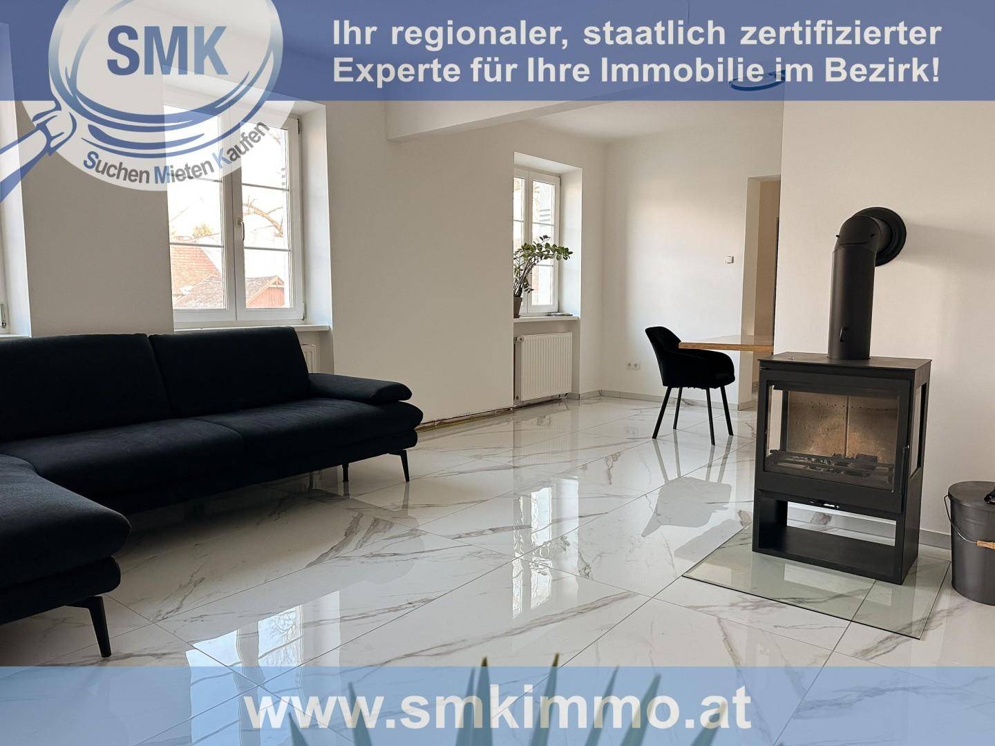 Gemütliches Wohnzimmer mit modernem Kaminofen, schwarzem Sofa und hellen Fliesen.