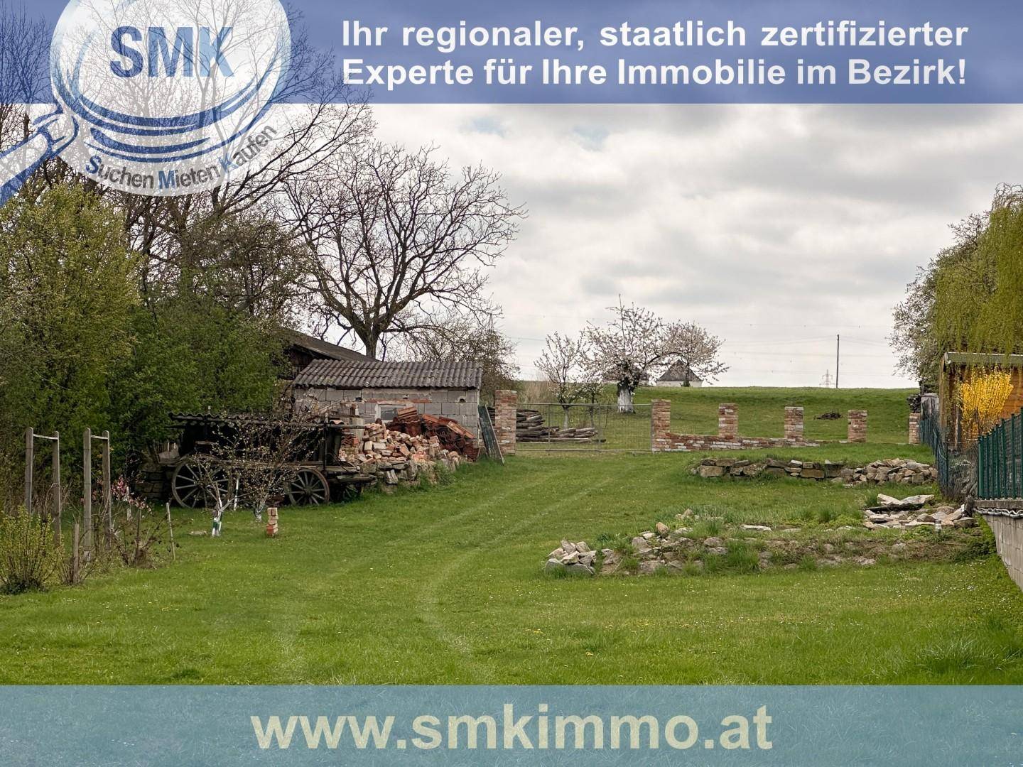 Weitläufiger Gartenbereich mit Rasenfläche, alten Gebäuden und Bäumen im Hintergrund.