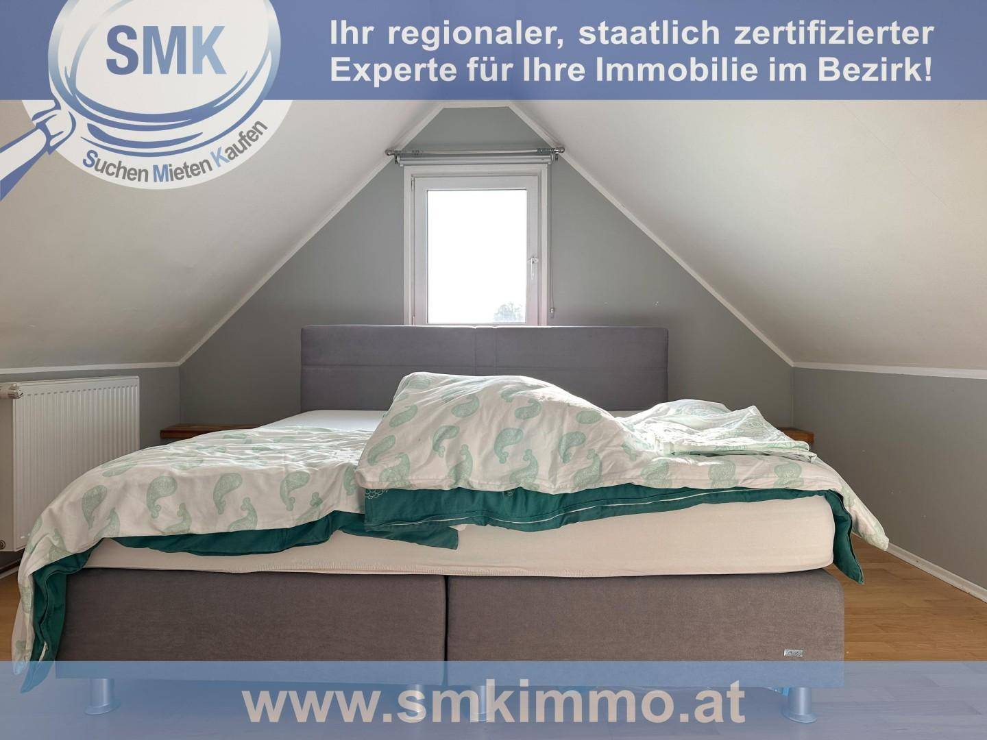 Schlafzimmer im Dachgeschoss mit gemütlichem Bett, Dachschräge und Fenster.