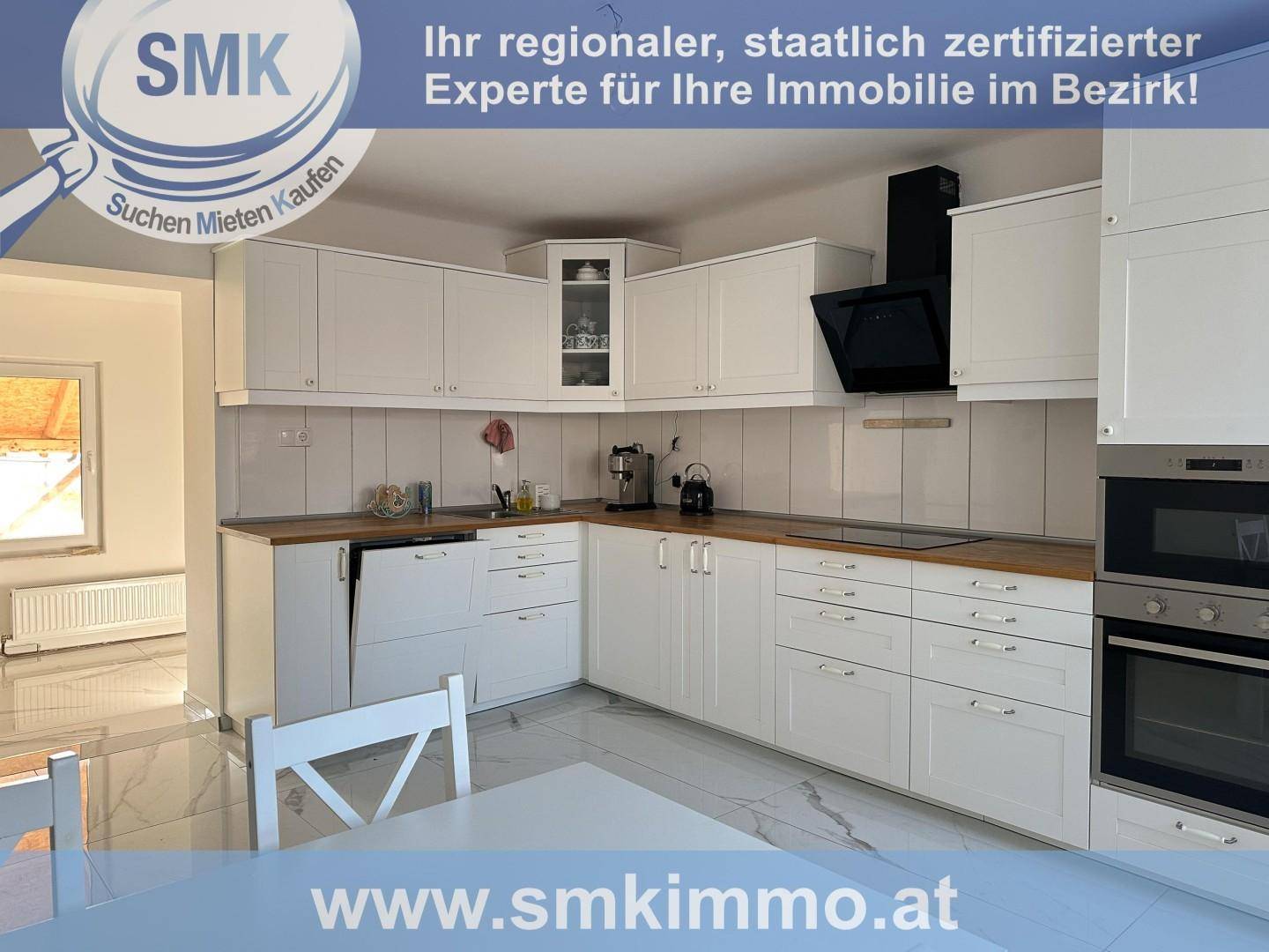 Moderne weiße Küche mit Holzarbeitsplatten, integrierten Geräten und Fliesenboden.