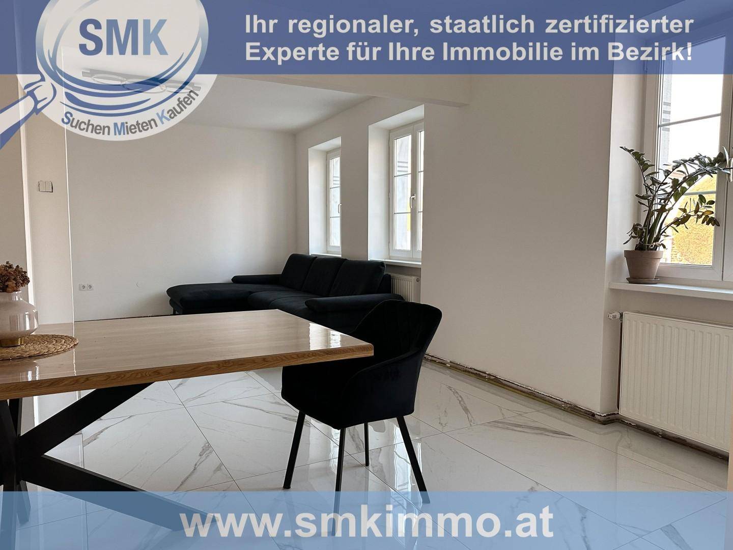 Offener Wohn-Essbereich mit modernem Esstisch, schwarzem Sofa und glänzenden Fliesen.