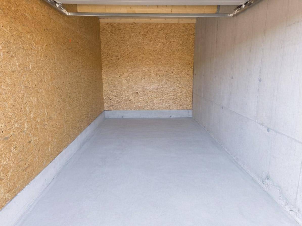 Geräumige Lagerhalle mit OSB-Platten an einer Wand und Betonwänden an der anderen Seite.