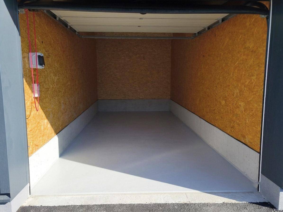 Leere Lagerhalle mit OSB-Platten an den Wänden und einem hellgrauen Boden.