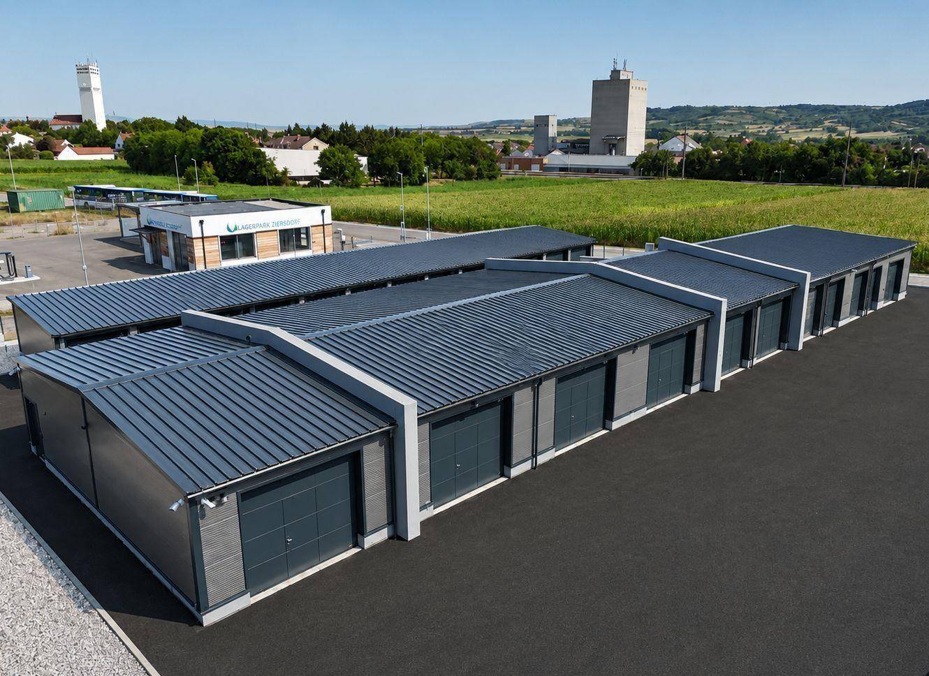Reihe von modernen Garagenlagereinheiten mit dunklen Rolltoren und ländlicher Umgebung.