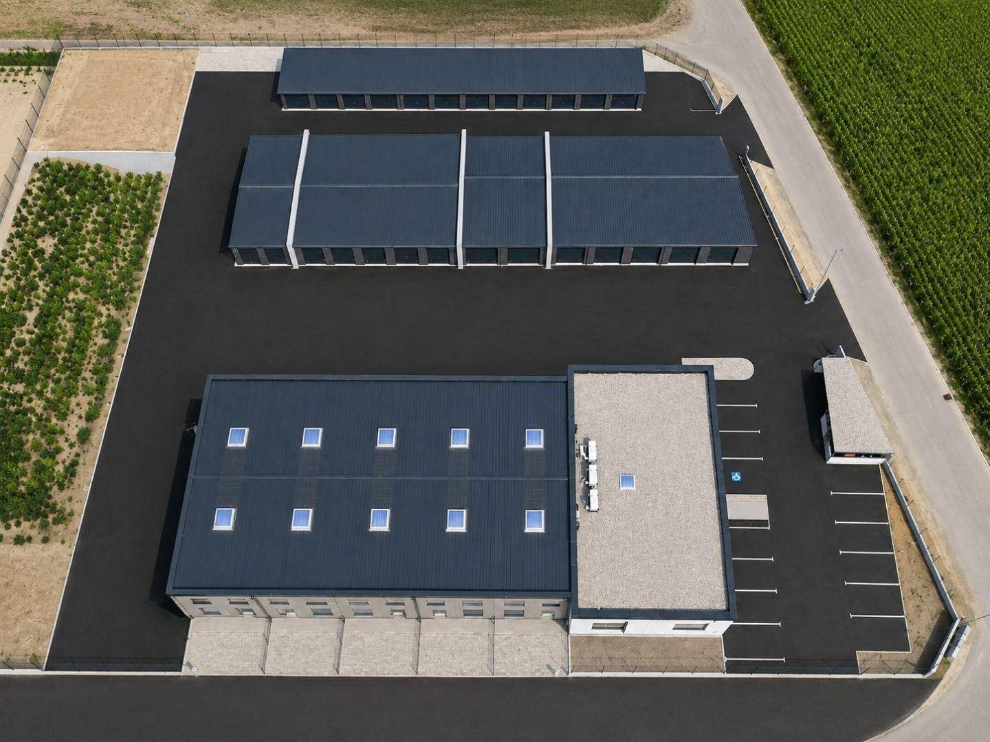 Draufsicht aus der Luft auf den gesamten Gewerbekomplex mit Gebäuden und Parkplatzanordnung.