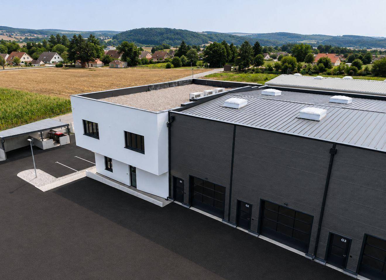 Nahaufnahme aus der Luft des Bürogebäudes und der angrenzenden Lagerhallen mit Parkflächen.