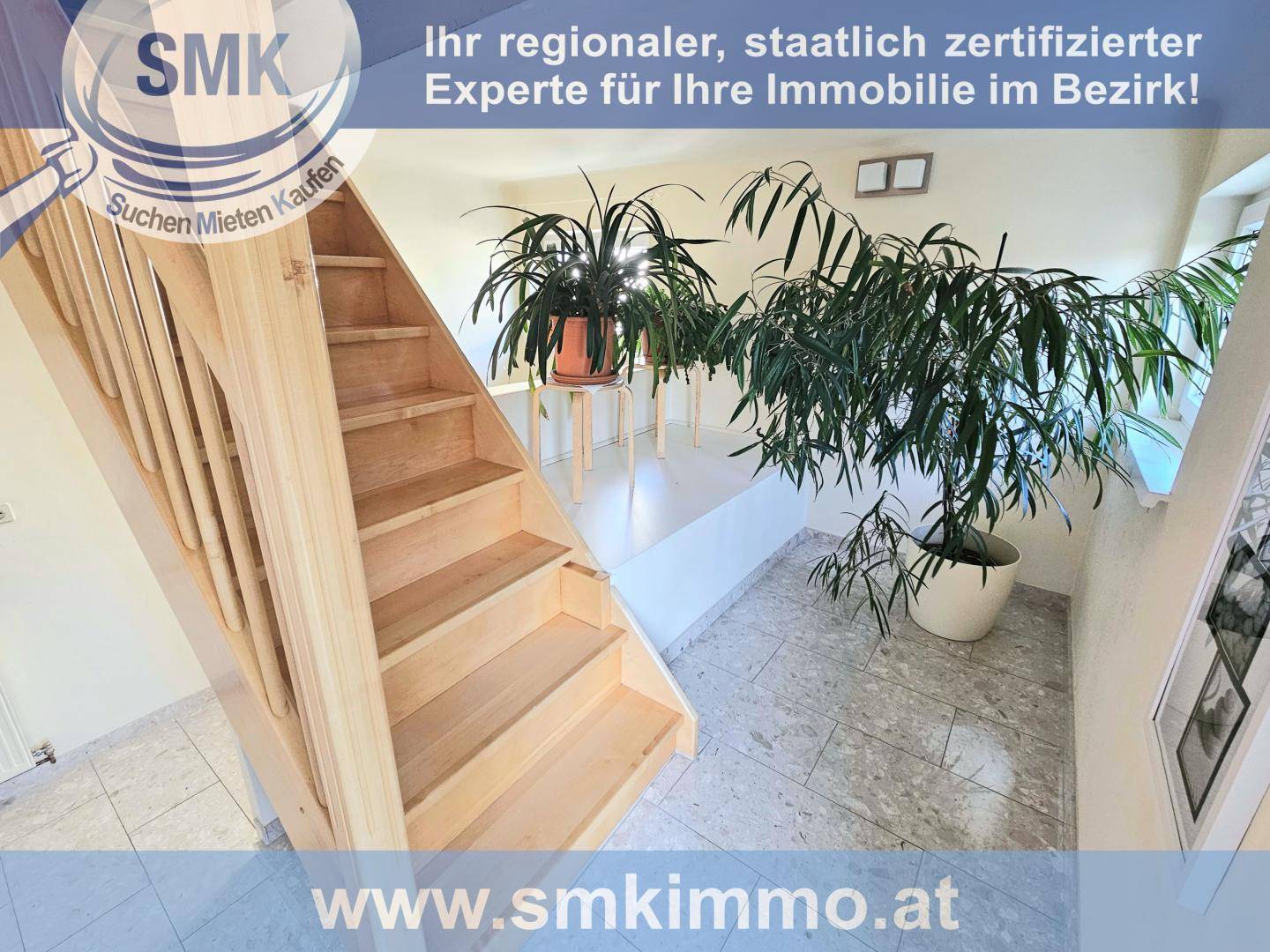 Heller Eingangsbereich mit Holztreppe und Fliesenboden, geschmückt mit Zimmerpflanzen.