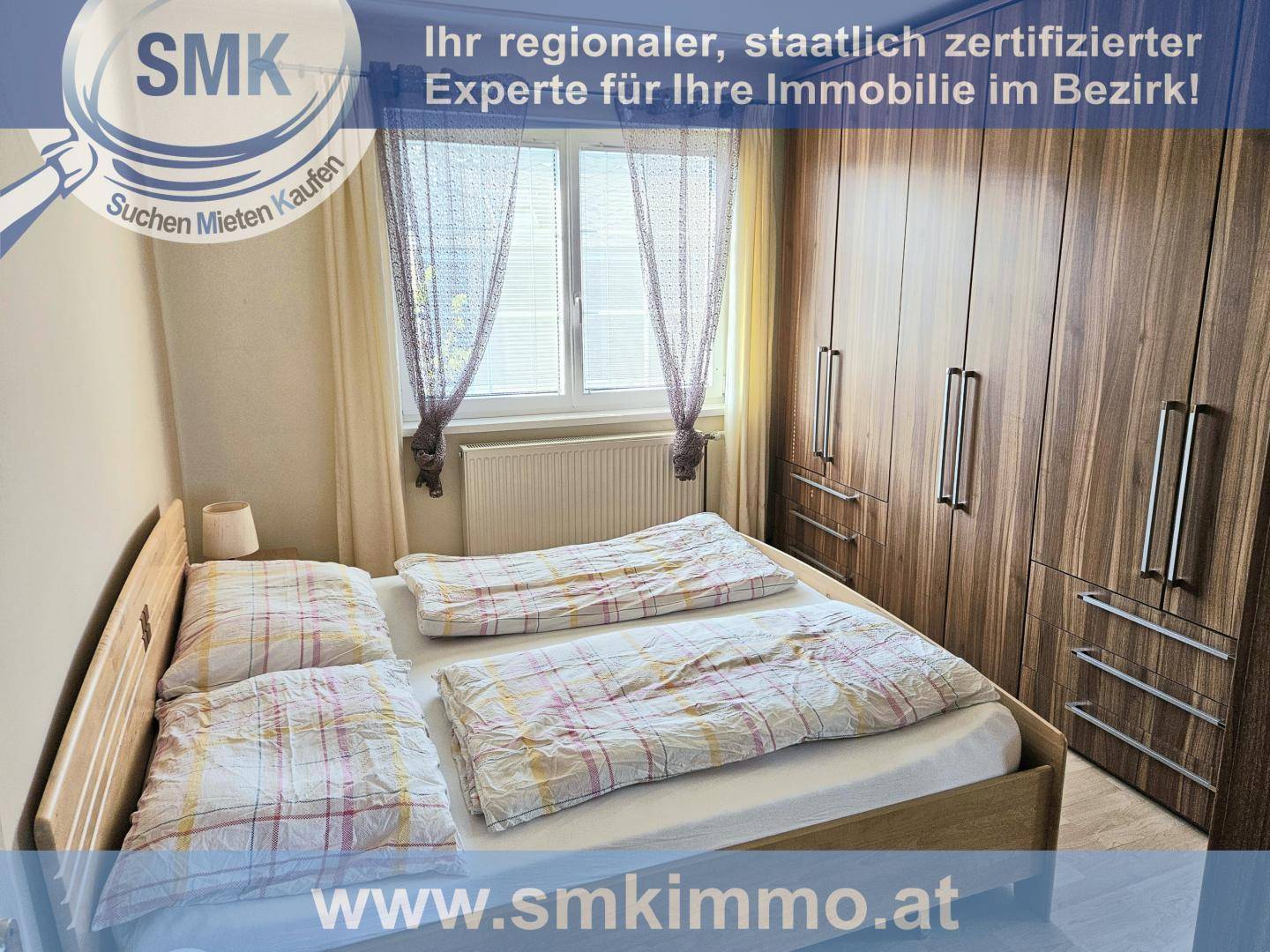 Schlafzimmer mit Doppelbett, großem Kleiderschrank und Fenster mit Vorhängen.