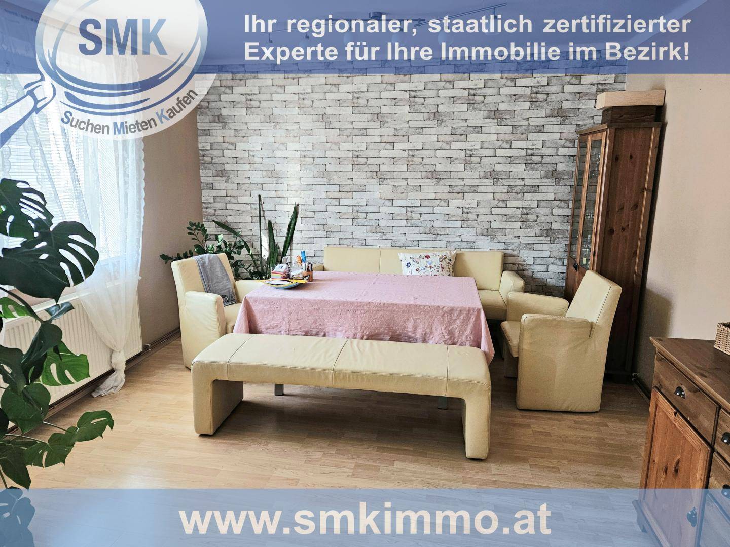 Essbereich mit hellem Holzboden, Esstisch und Stühlen vor einer Ziegelwand.