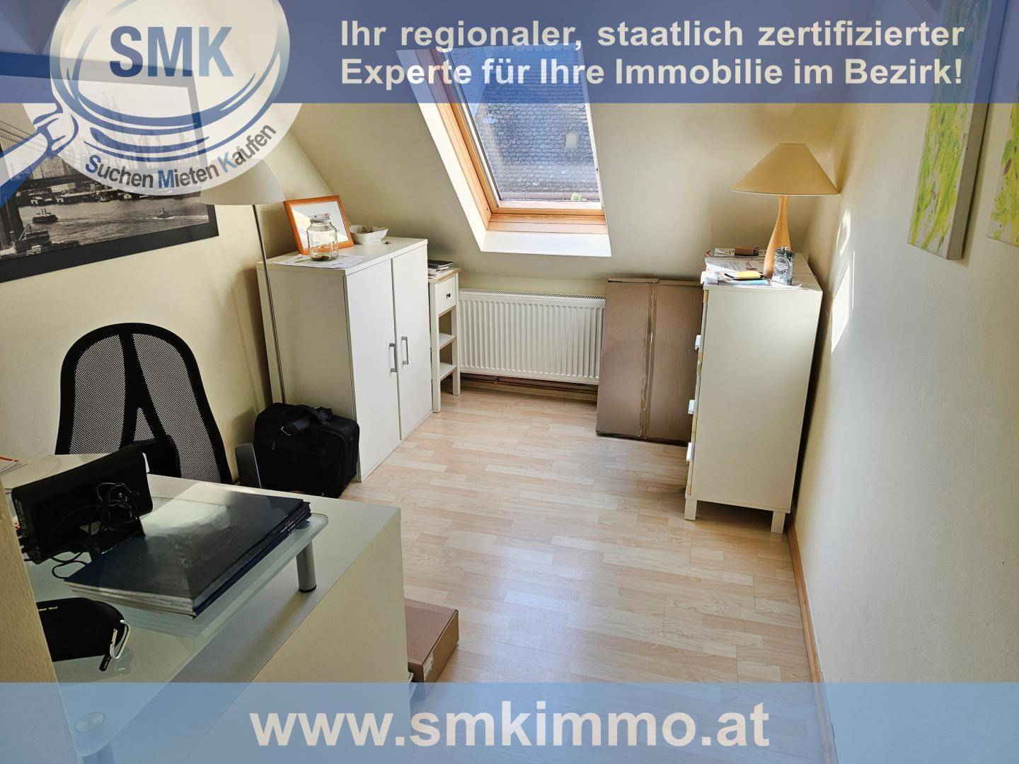 Dachgeschoss-Büro mit Schreibtisch, Schränken, Dachfenster und Laminatboden.
