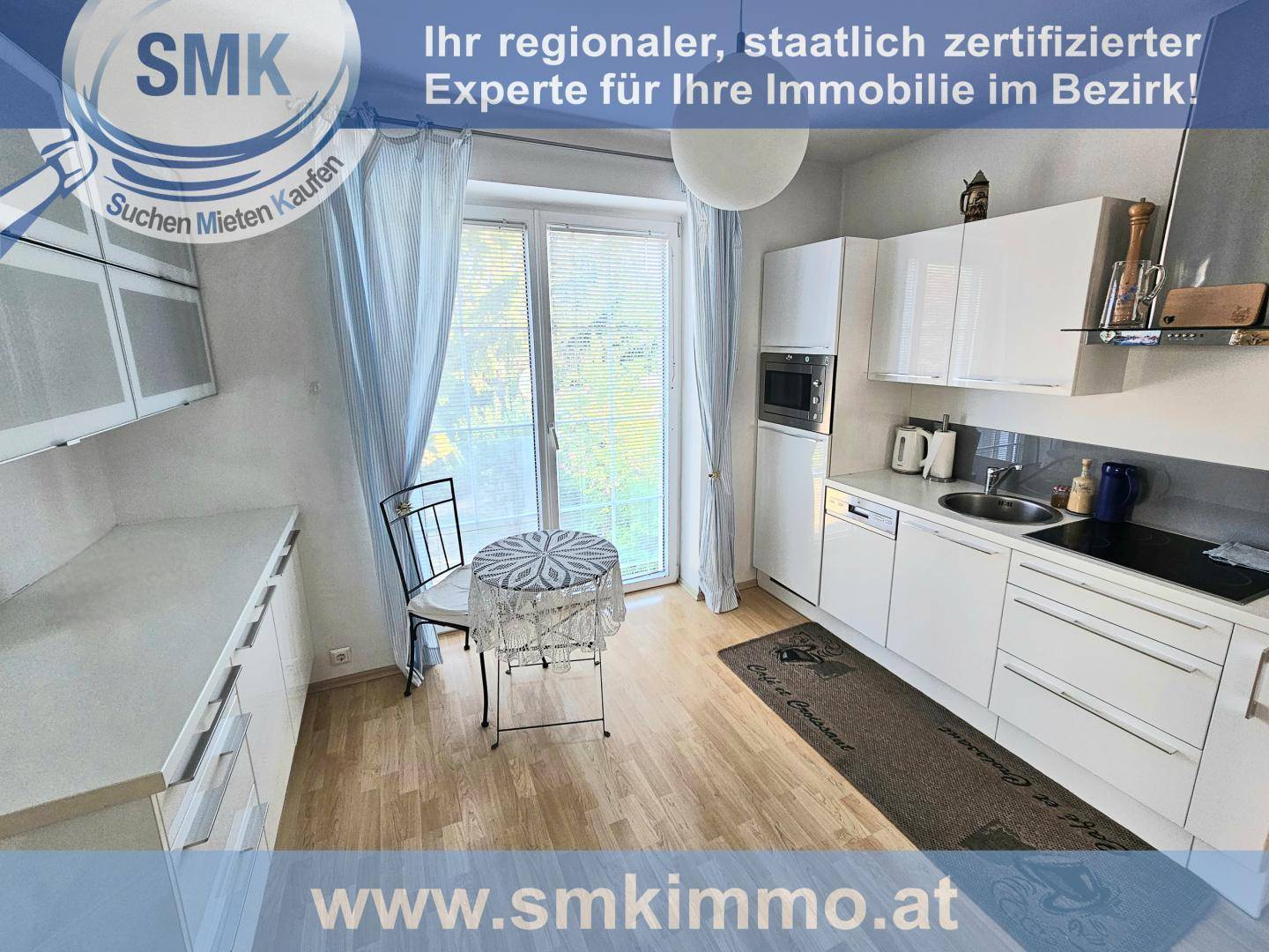 Helle Küche mit weißen Hochglanzschränken, Holzboden und Zugang zu einem französischen Balkon.