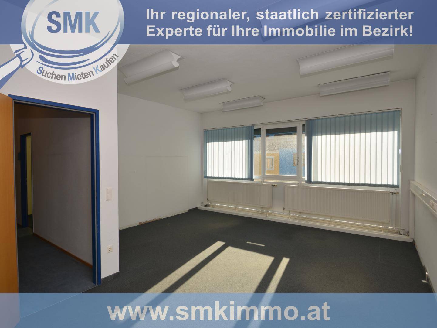 Leerer Büroraum mit dunklem Teppichboden und mehreren Fenstern mit Jalousien für Privatsphäre.