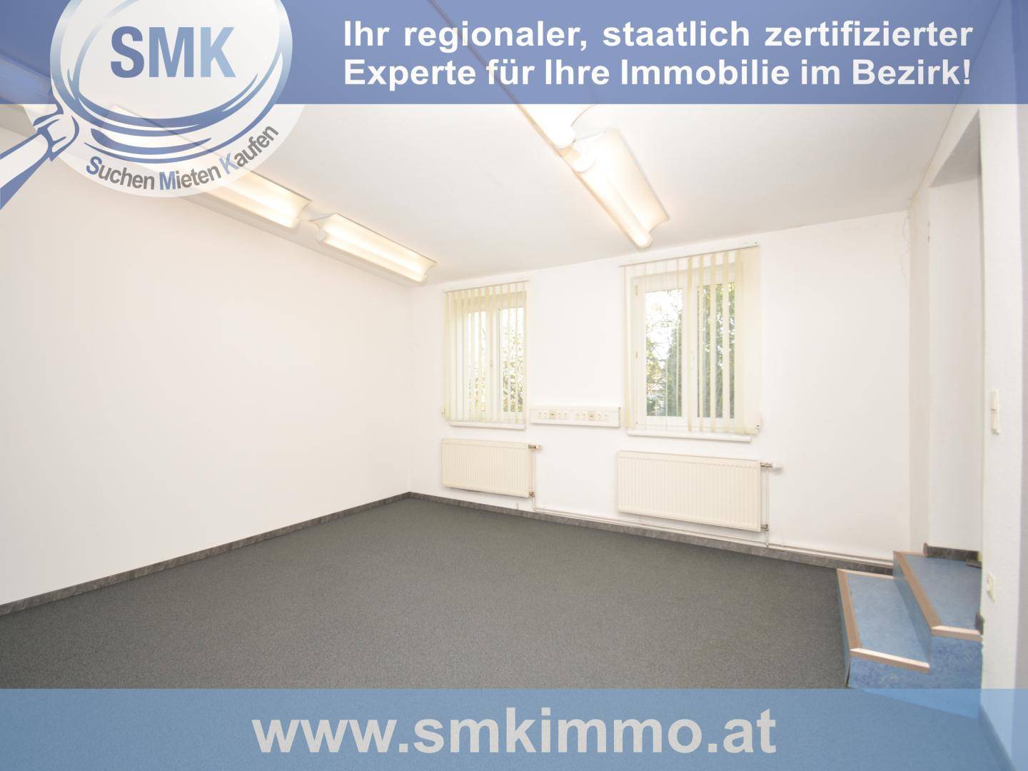 Leerer Büroraum mit dunklem Teppichboden und zwei Fenstern mit Jalousien, hell und funktional.