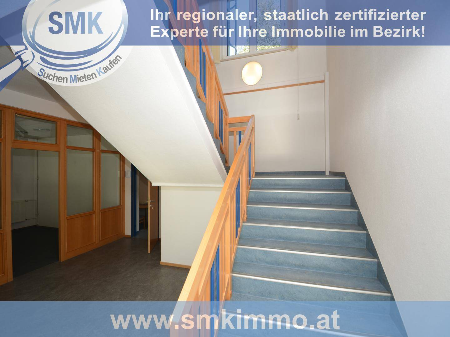 Treppenhaus mit blauen Stufen und Holzgeländer, führt in die oberen Etagen des Gebäudes.
