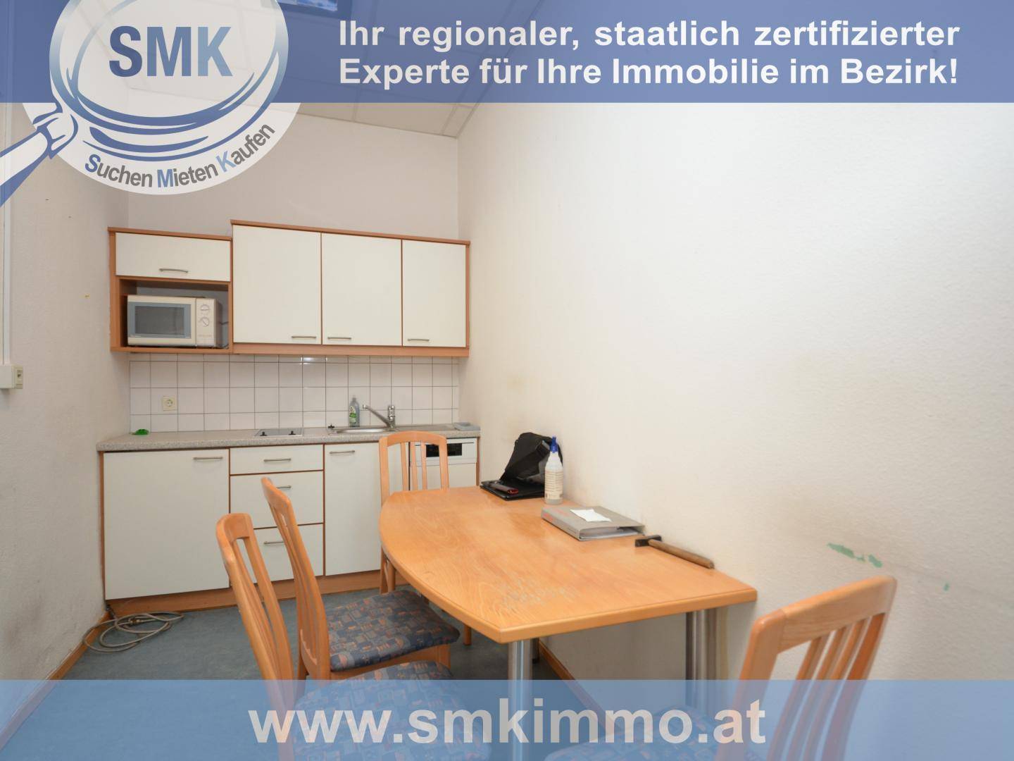 Kleine Küchenzeile mit weißen Schränken, Mikrowelle und Esstisch für eine schnelle Mahlzeit.