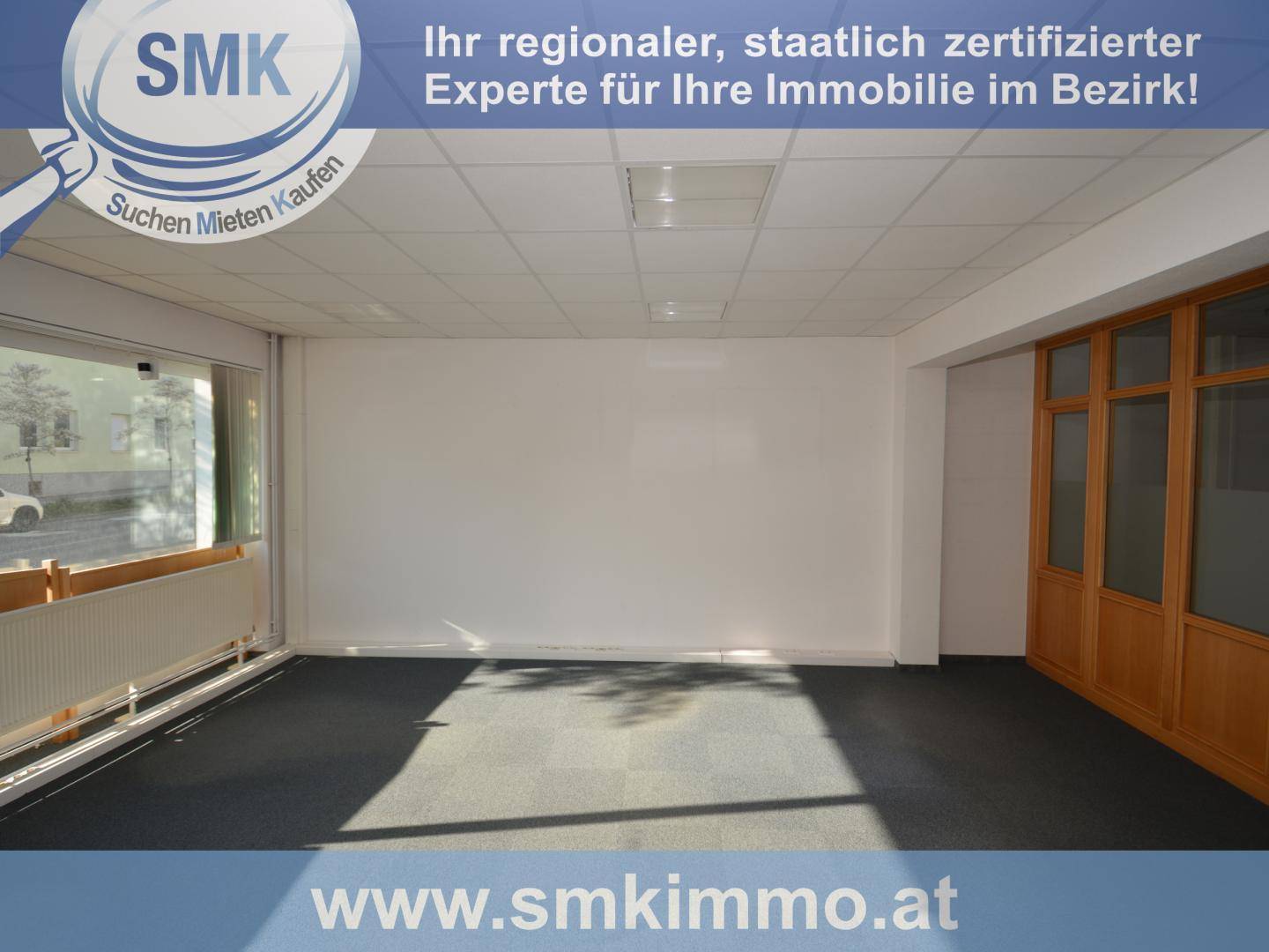 Leerer Büroraum mit dunklem Teppichboden und großen Fenstern, bietet viel natürliches Licht.