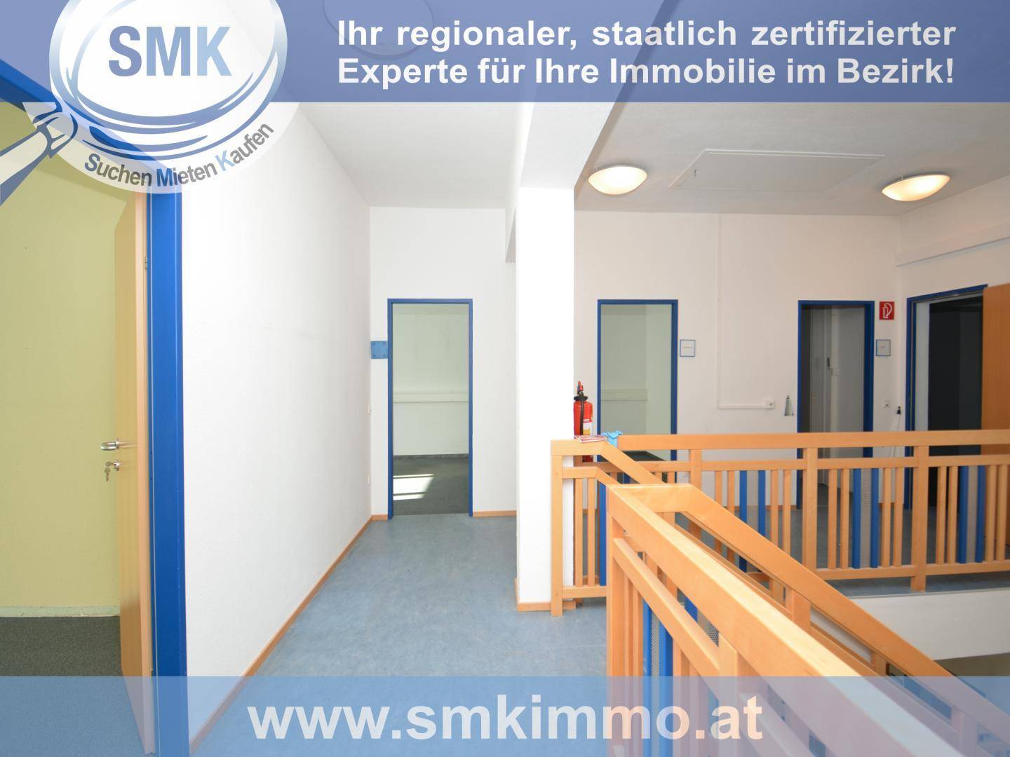 Geräumiger Flur mit Holzgeländer und blauen Türen, führt zu weiteren Räumen im Gebäude.