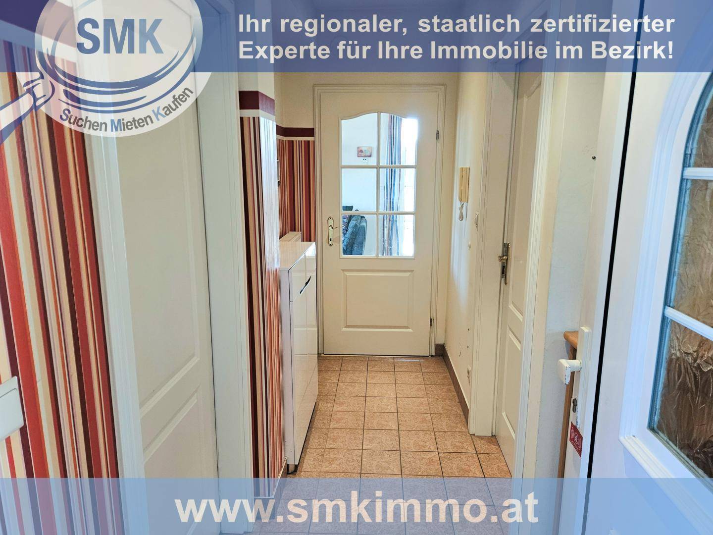 Heller Flur mit Fliesenboden, weißen Schränken und einer Eingangstür mit Glaseinsatz.
