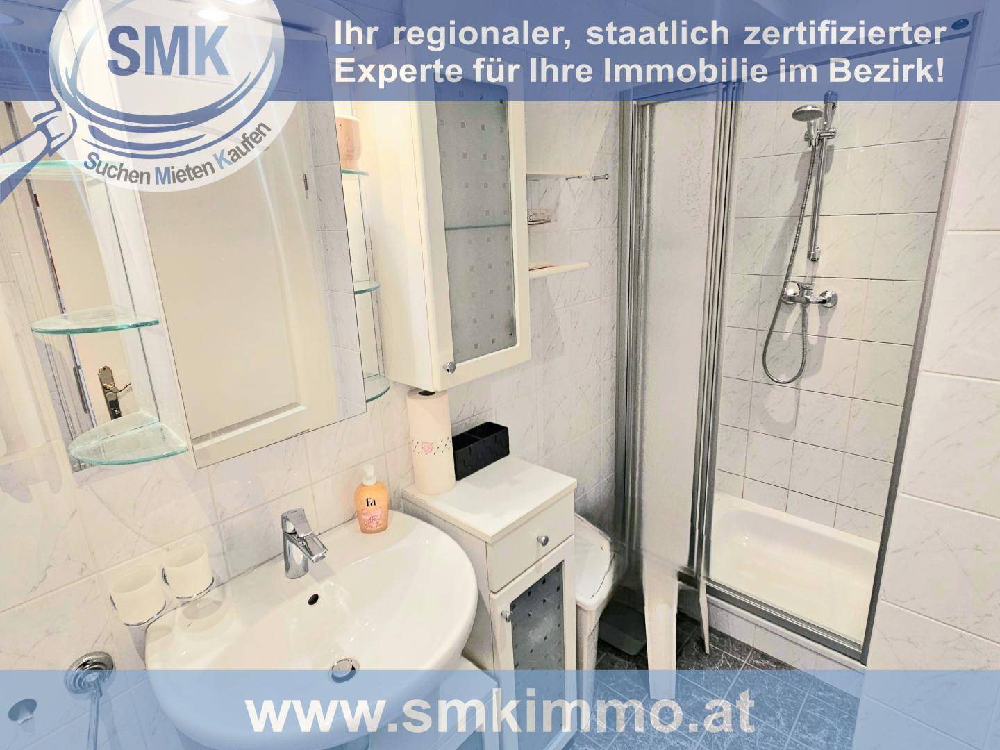 Kleines Badezimmer mit Dusche, Waschbecken und WC, komplett gefliest in Weiß.