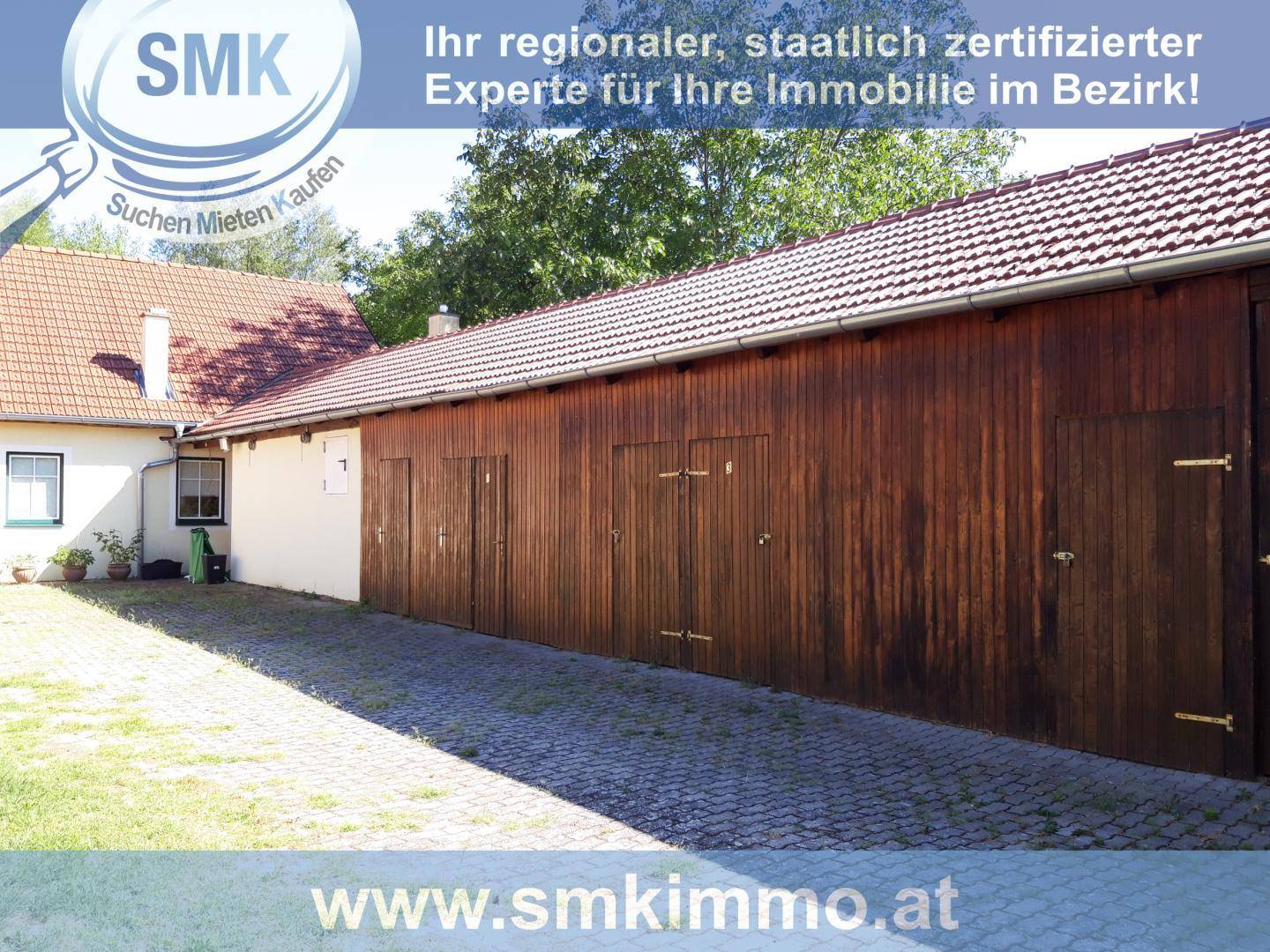 Lange Reihe von Holzgaragen oder Lagerräumen mit gepflasterter Zufahrt.