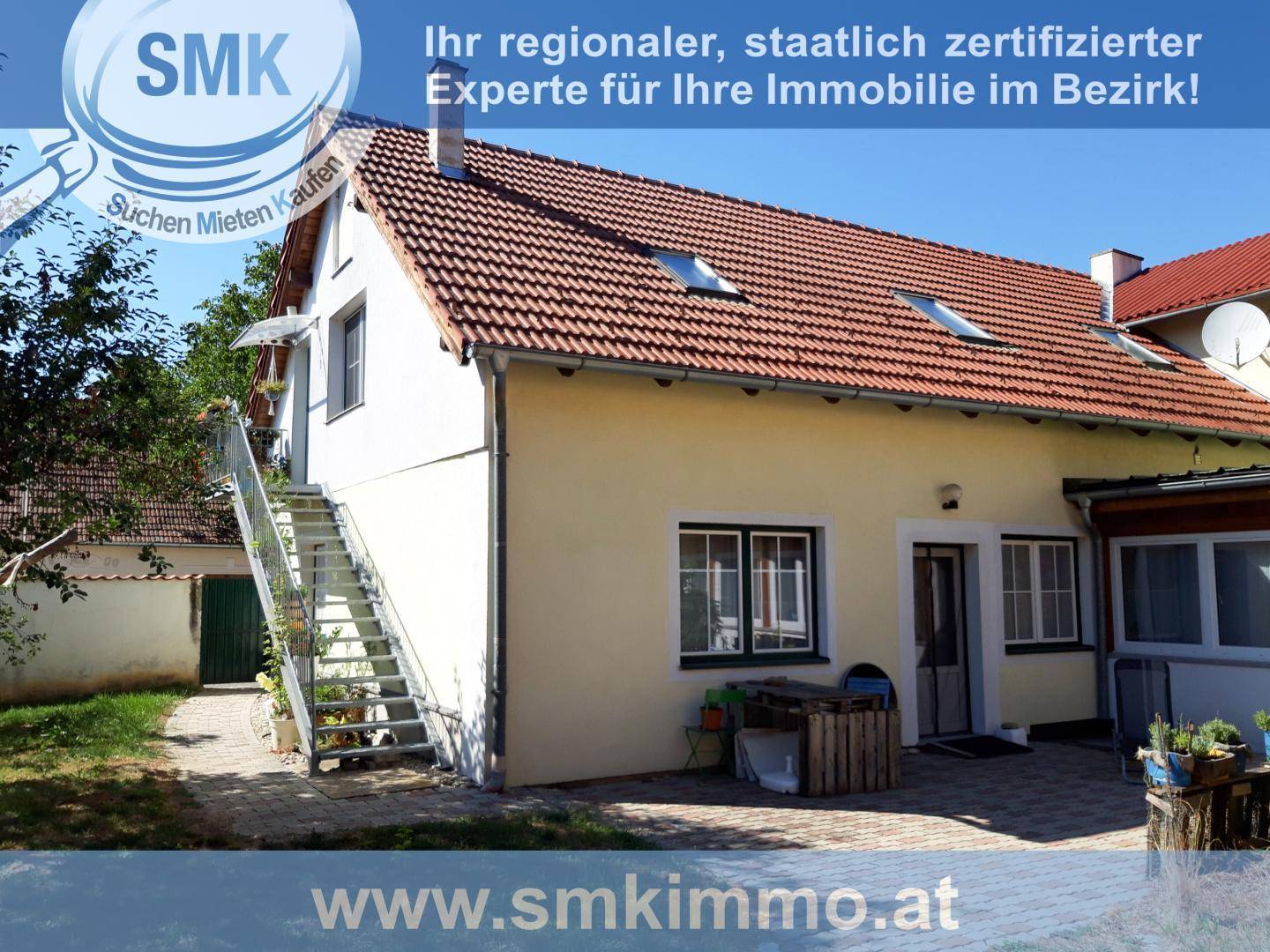 Außenansicht des Gebäudes mit Außentreppe, rotem Ziegeldach und einem gepflasterten Terrassenbereich.