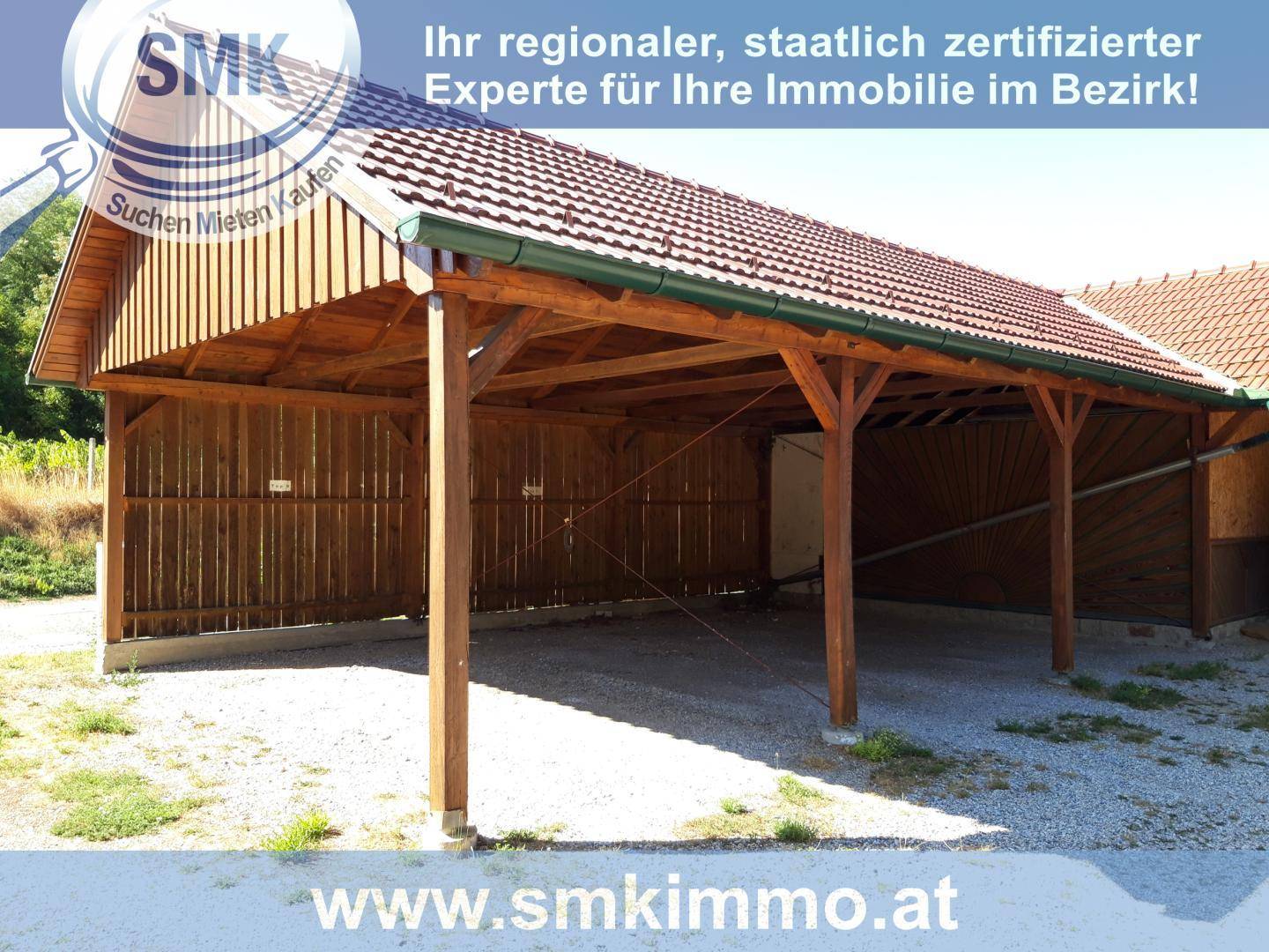Geräumiger Holzcarport mit Ziegeldach, bietet Schutz für Fahrzeuge.