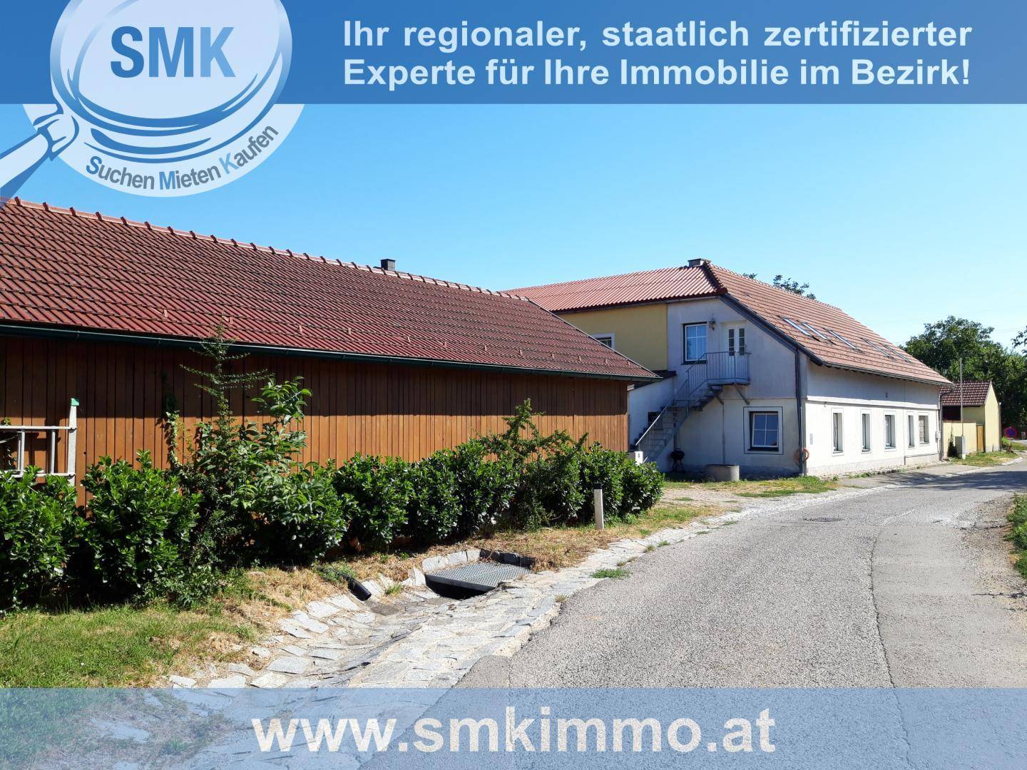 Langes Holzgebäude neben dem Haupthaus, gesehen von einem unbefestigten Weg aus.