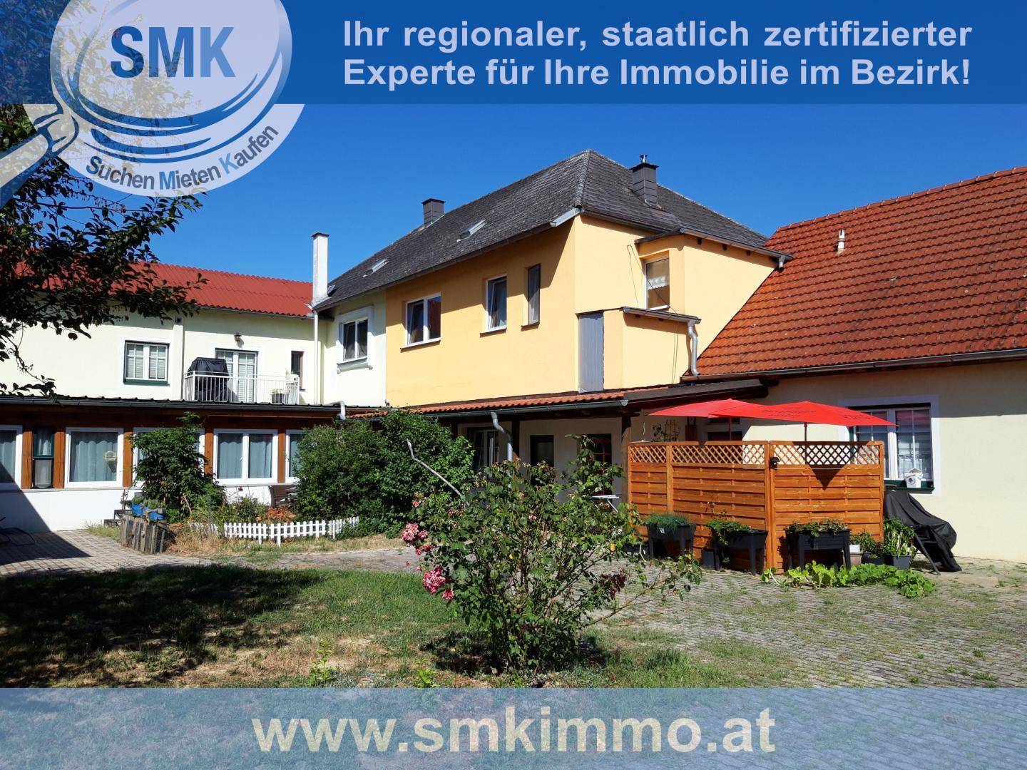 Außenansicht des Gebäudes mit einem kleinen Gartenbereich und einer Terrasse mit Sonnenschirm.