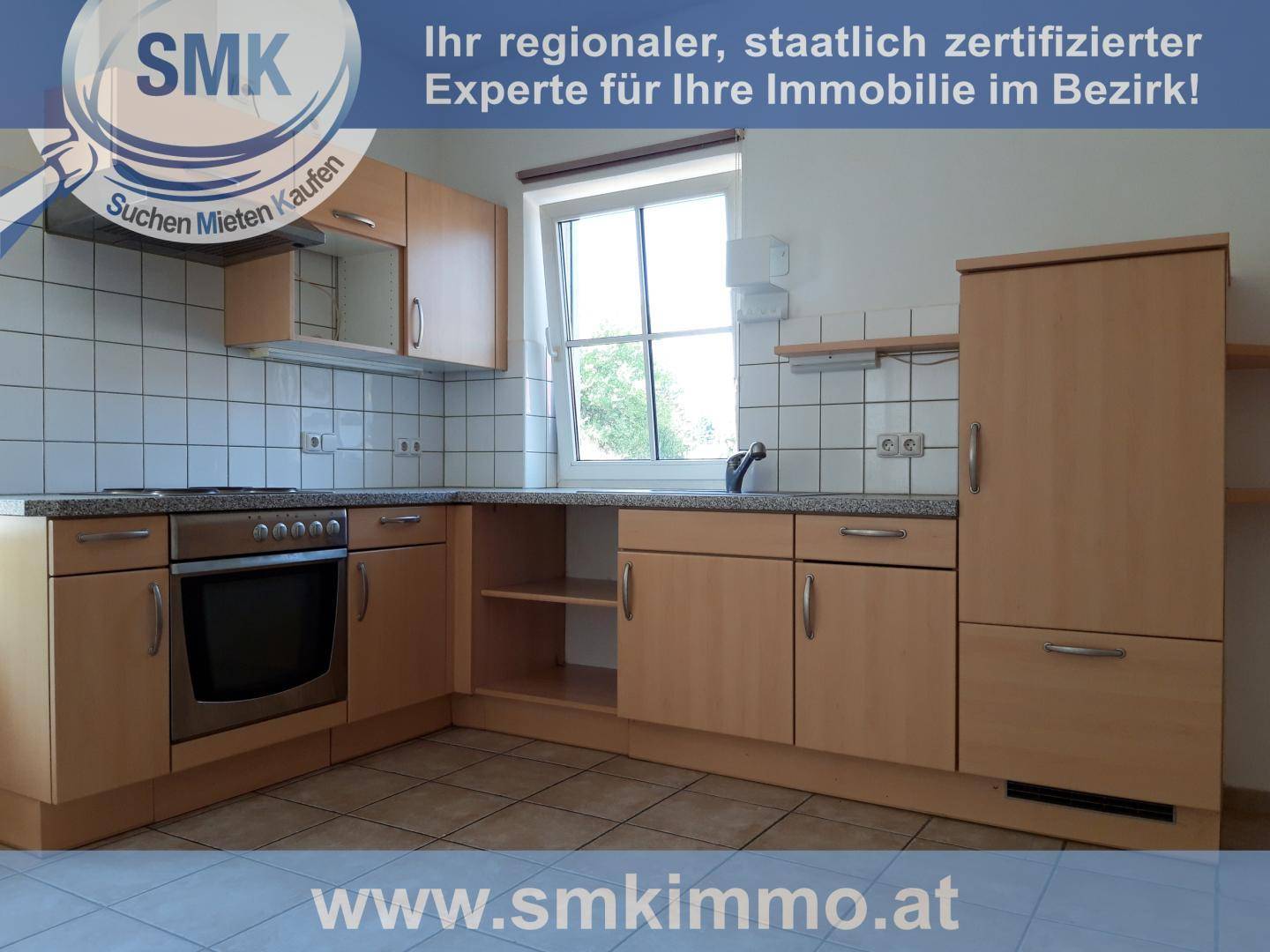 Funktionale Küche mit hellen Holzschränken, Einbauherd und gefliestem Boden.