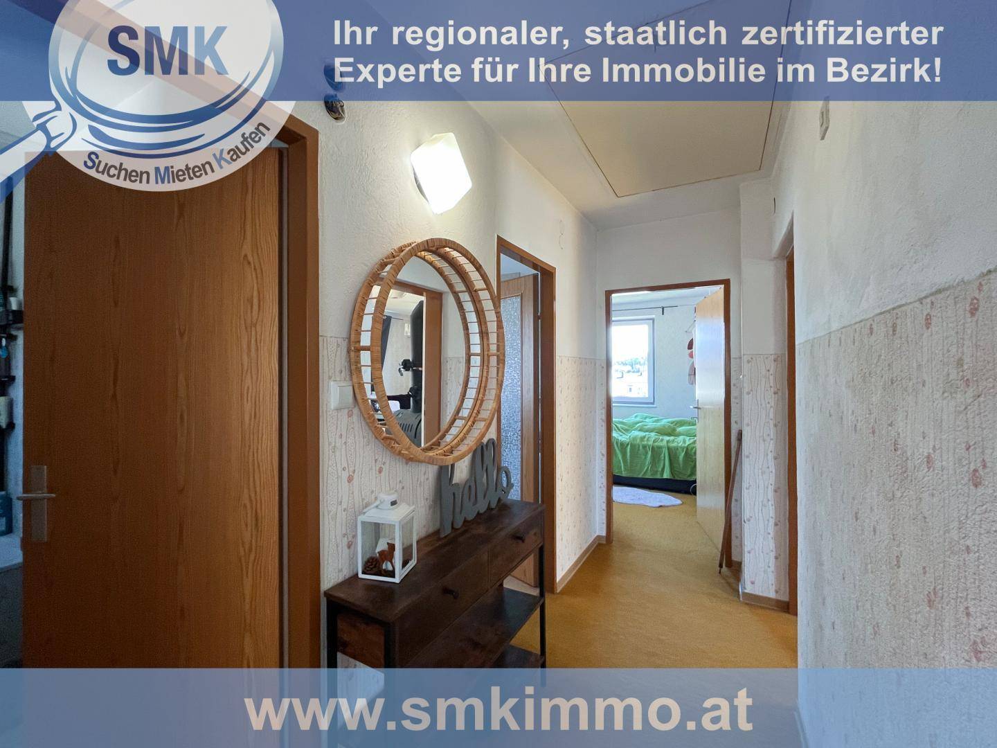 Gepflegter Flur mit gemusterter Tapete und Zugang zu einem Schlafzimmer im Hintergrund.