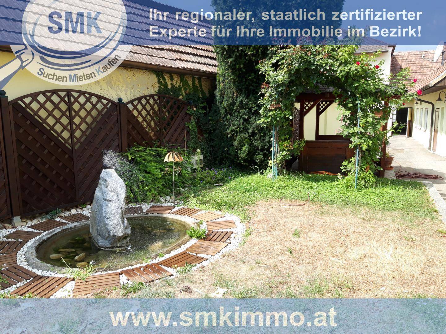 Gartenbereich mit kleinem Teich, Holzpavillon und dekorativem Zaun.