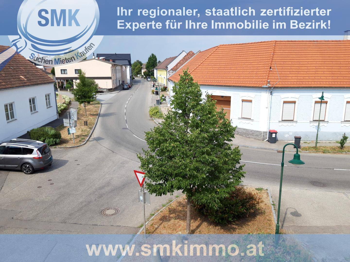 Blick von oben auf eine ruhige Wohnstraße mit traditionellen Häusern und Bäumen.