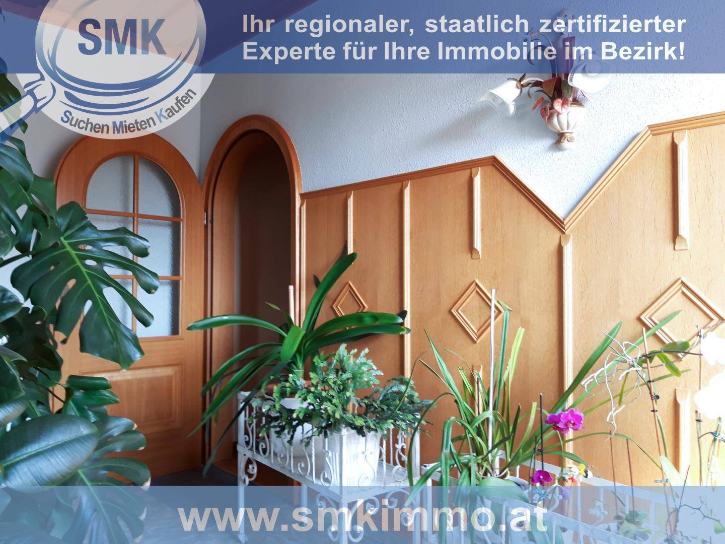 Eingangsbereich mit Holztäfelung, dekorativen Pflanzen und einer Rundbogentür.