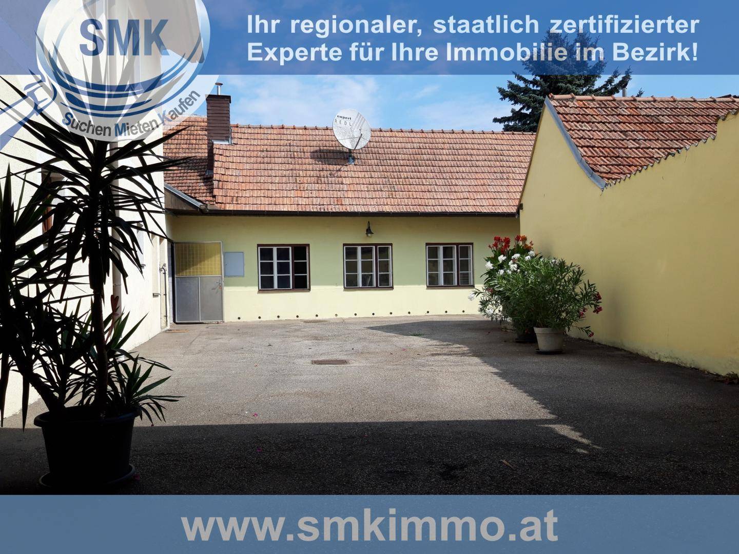 Hinterhof mit großem gepflastertem Bereich, Topfpflanzen und Blick auf die Gebäuderückseite.