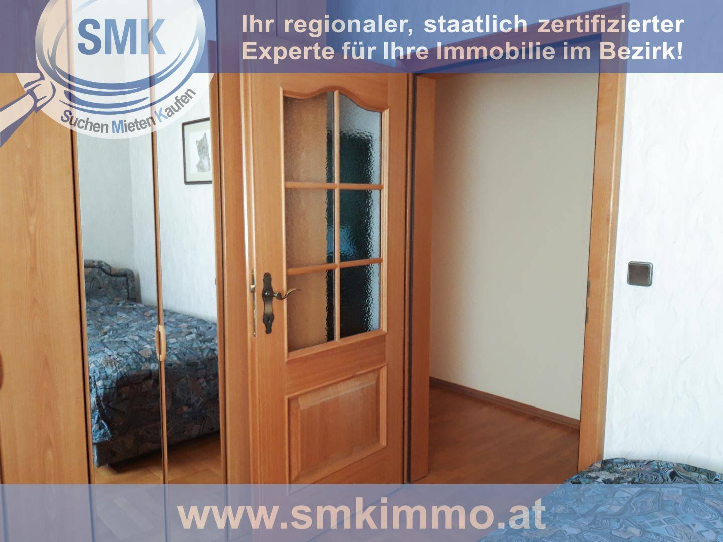 Schlafzimmer mit Spiegelschrank und Holztür, die zu einem weiteren Raum führt.
