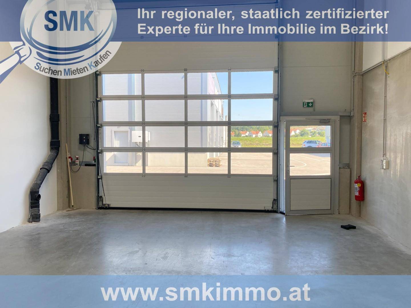 Helle Industriehalle mit großem, verglastem Rolltor und separater Zugangstür, ideal für Lager oder Produktion.