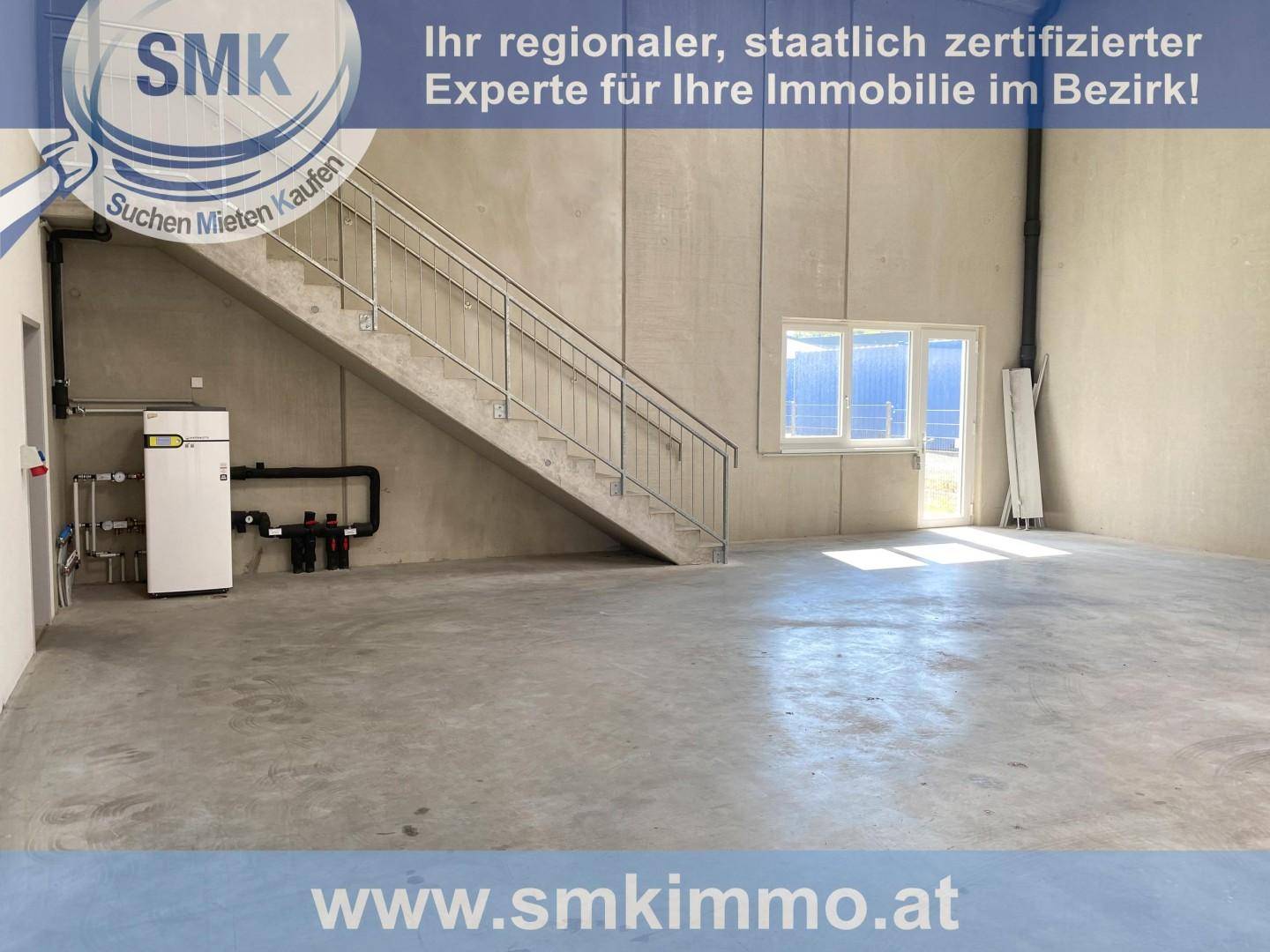 Große, offene Halle mit Betontreppe zum Obergeschoss und sichtbarer Heizungsanlage, bereit für den Ausbau.
