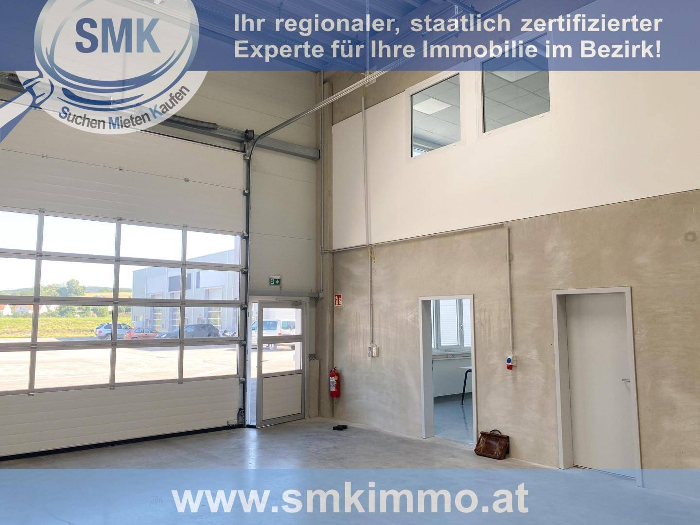 Geräumige Industriehalle mit großem Rolltor, separatem Eingang und Blick auf den Außenbereich.
